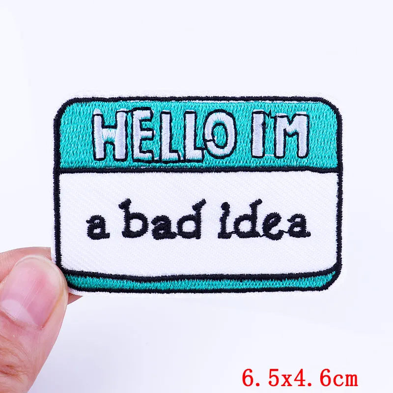 An embroidered patch with the text HELLO I'M a bad idea on a teal and white background.