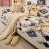 A beige and gray patterned fleece sofa slipcover with faux fur pillows and a long cream throw blanket.