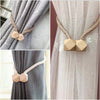 Gold-toned magnetic curtain tiebacks with beige geometric accents on sheer and gray fabric.