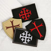 Three embroidered military cross shield patches in black and tan on a white fabric background.