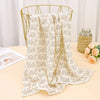 A beige floral printable cotton crib sheet draped over a gold wire hanger.