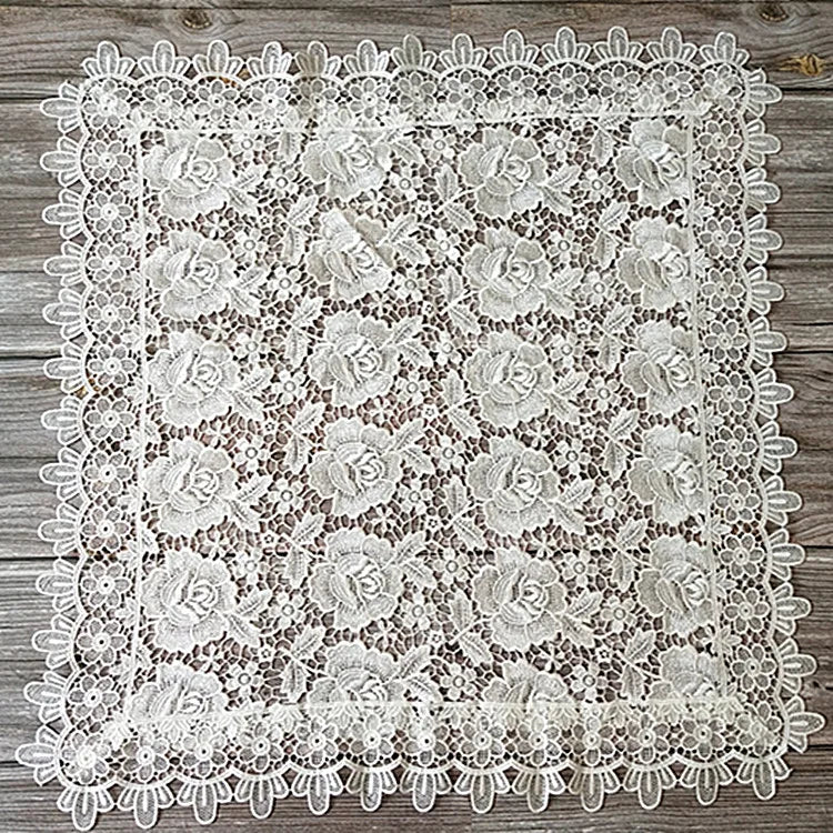 White floral lace tablecloth with scalloped edges on a wooden surface.