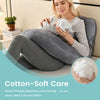 A woman is using a soft, white cotton pillow for support while sitting on an ergonomic maternity pillow.