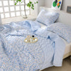 Light blue floral quilted quilt set with matching pillows displayed on a white bed.
