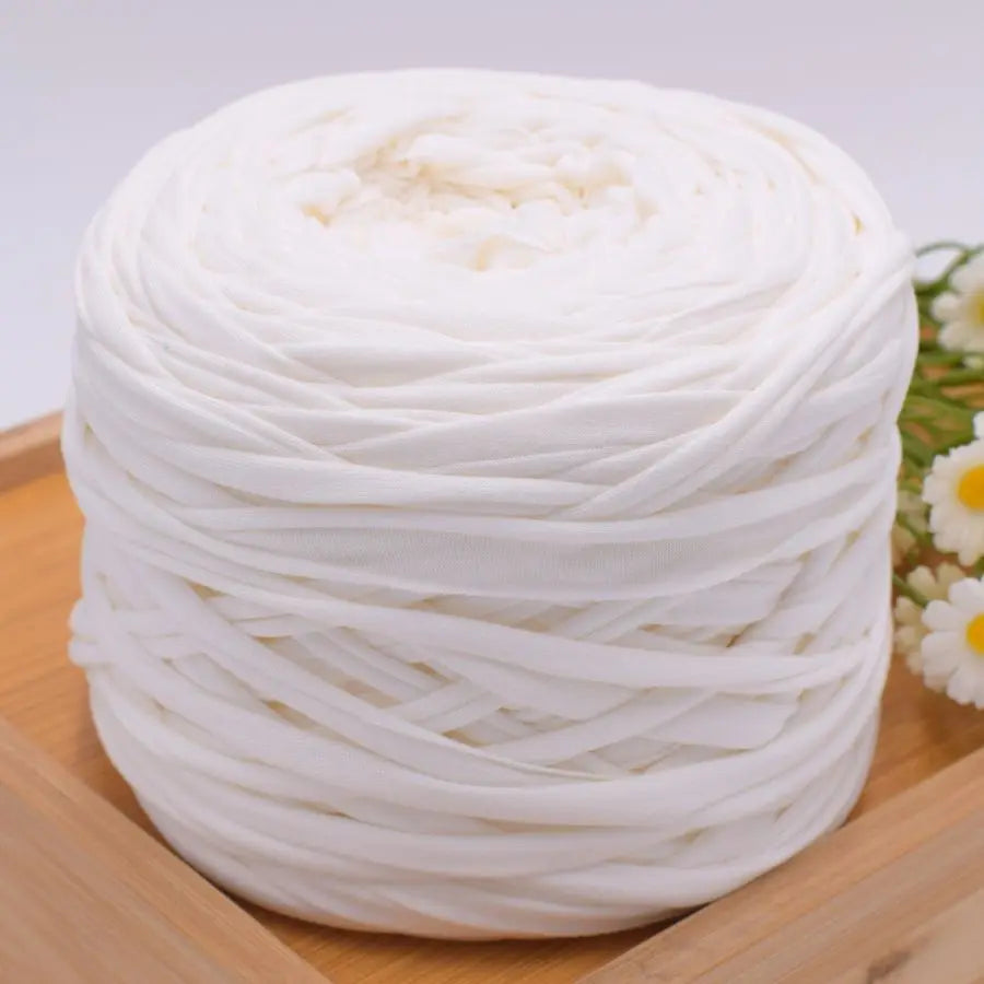 A ball of white polyester craft yarn is displayed on a wooden surface.