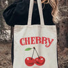 A white canvas shopping bag with red lettering spelling out CHERRY and a graphic of cherries.