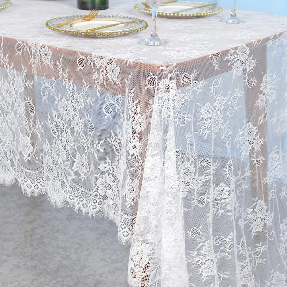 White embroidered floral lace table runner draped over a light pink tablecloth.