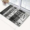 A rectangular black and white striped kitchen mat with the text SEASONED WITH LOVE is displayed on a white floor.