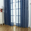 Blue sheer curtains with silver star patterns hanging in a window.
