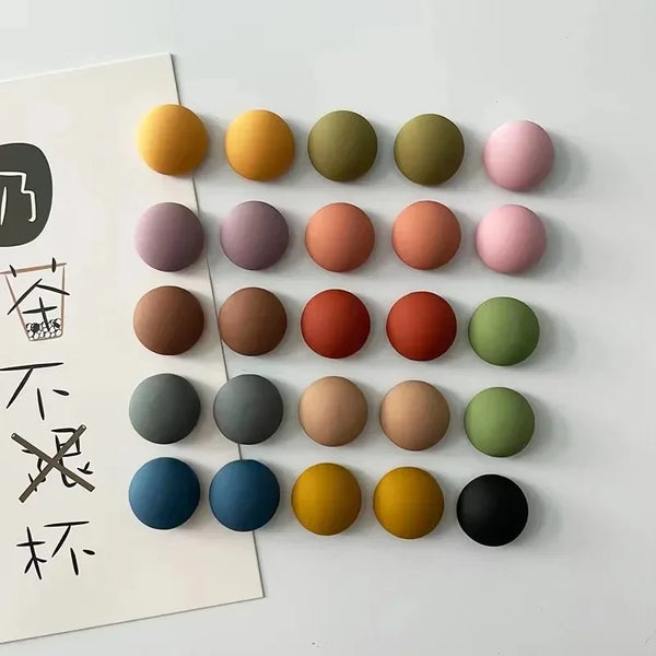 A set of ten frosted round fridge magnets in various muted and earthy tones arranged in a grid.