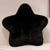 A black, star-shaped decorative throw pillow is displayed on a white surface.