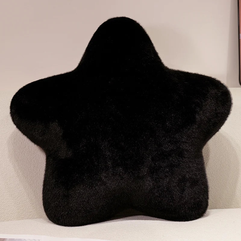 A black, star-shaped decorative throw pillow is displayed on a white surface.