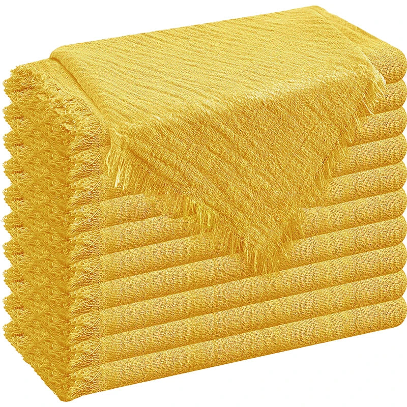 A stack of golden yellow decorative cloth napkins with fringed edges.