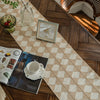 A boho farmhouse linen table runner laid on a dark wood surface with a framed picture and glass vase.