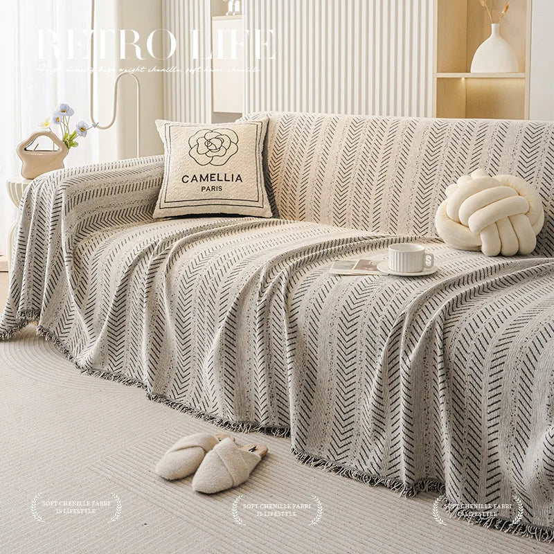 Elegant fishbone pattern sofa cover in beige and gray tones draped on a light-colored sofa.