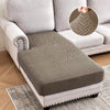 A gray jacquard stretch sofa cushion cover placed on a light-colored sofa and a rug.