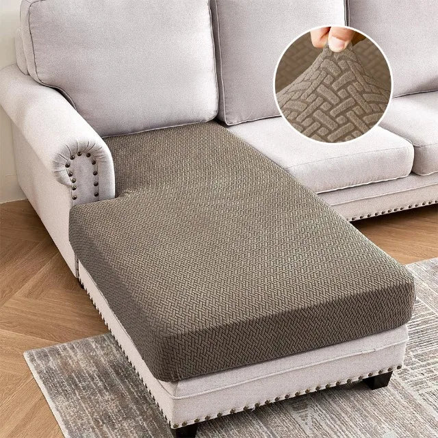 A gray jacquard stretch sofa cushion cover placed on a light-colored sofa and a rug.