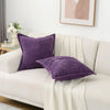 A purple striped corduroy lumbar support pillow cushion resting on a white sofa.
