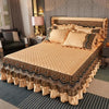 A bed dressed with an elegant velvet skirt featuring gold and brown patterns on a quilted beige bedspread.