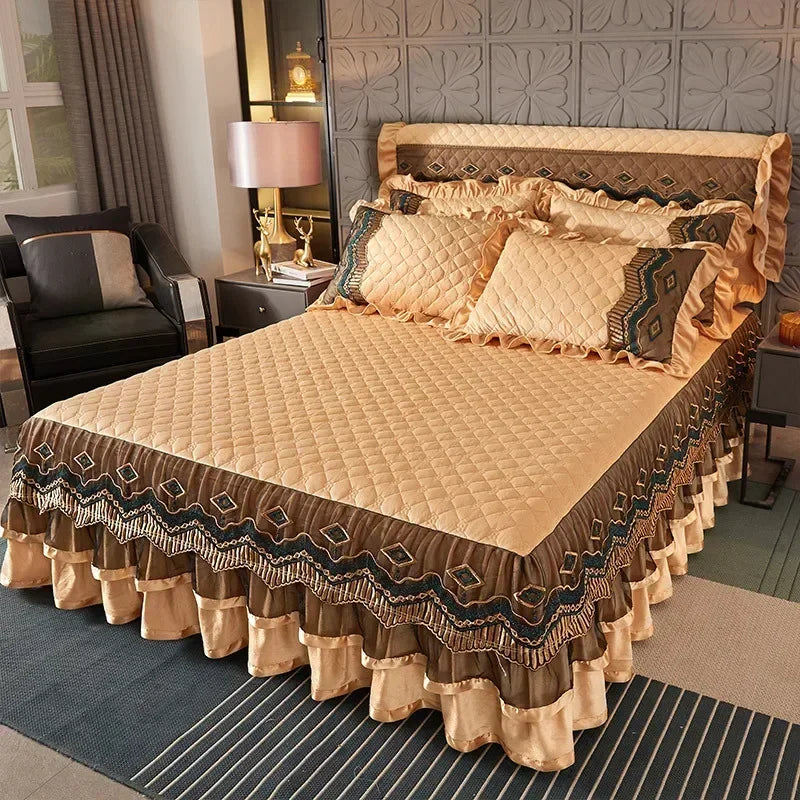 A bed dressed with an elegant velvet skirt featuring gold and brown patterns on a quilted beige bedspread.