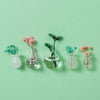 A collection of mini ceramic landscape fridge magnets featuring pink and blue floral designs on a light green background.