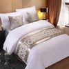 White bedding with decorative gold and white patterned bed flags on pillows.