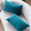 Two teal velvet decorative pillow covers resting on a white textured sofa or chair.