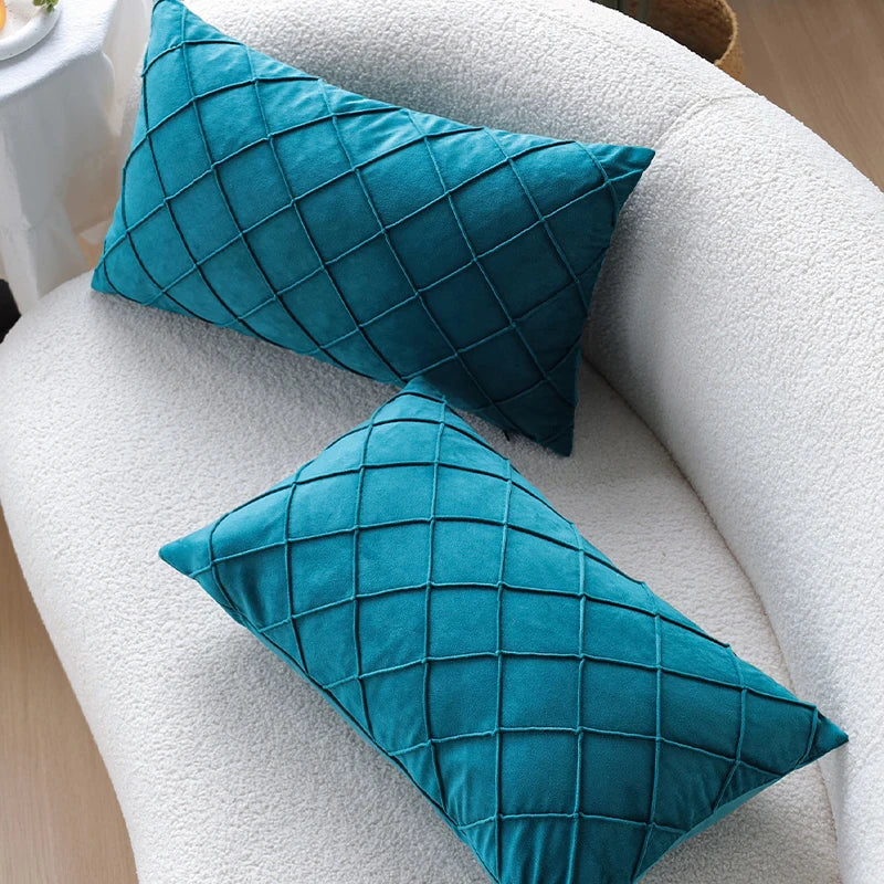 Two teal velvet decorative pillow covers resting on a white textured sofa or chair.