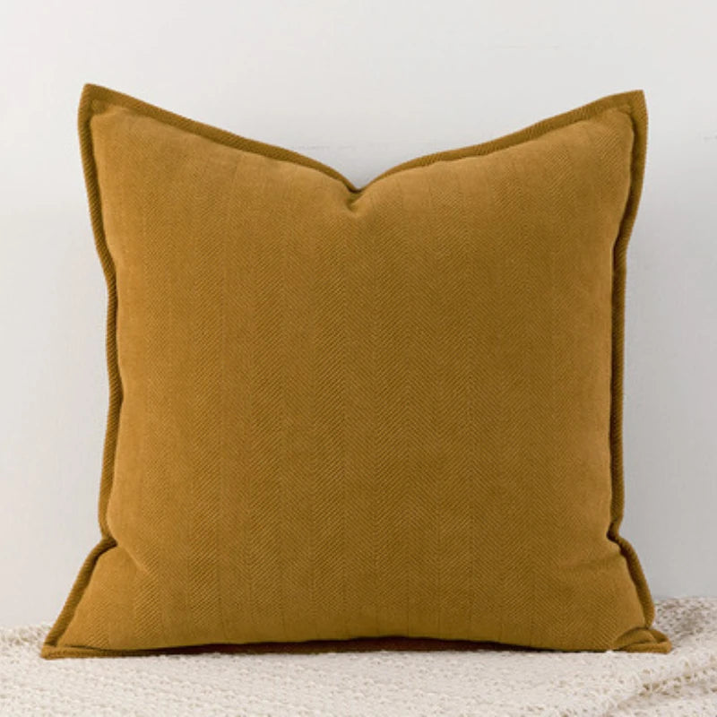 A solid mustard yellow chenille throw pillow with a scalloped edge.