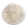A round, fluffy, light beige faux fur sheepskin area rug.