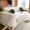 A cream-colored stretchable sofa cover with a vertical line pattern is shown on a light rug.