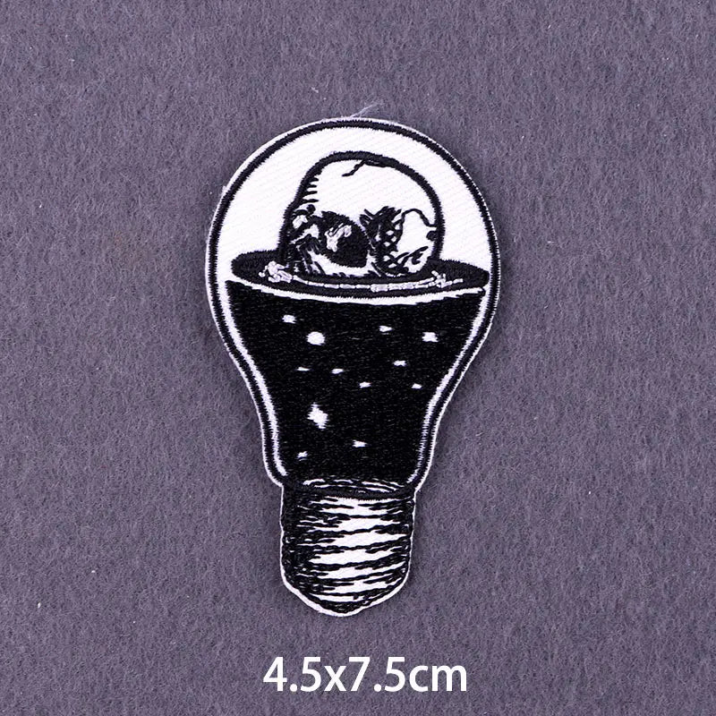 A black embroidered patch shaped like a light bulb containing a 3D skull.