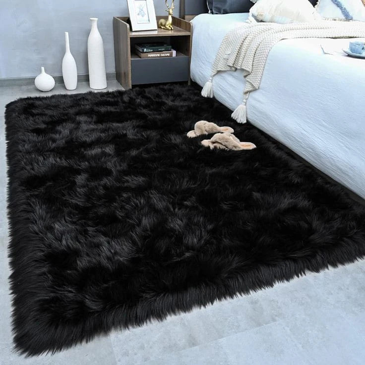 A fluffy black velvet anti-slip floor mat placed on a light gray floor next to a white bed.