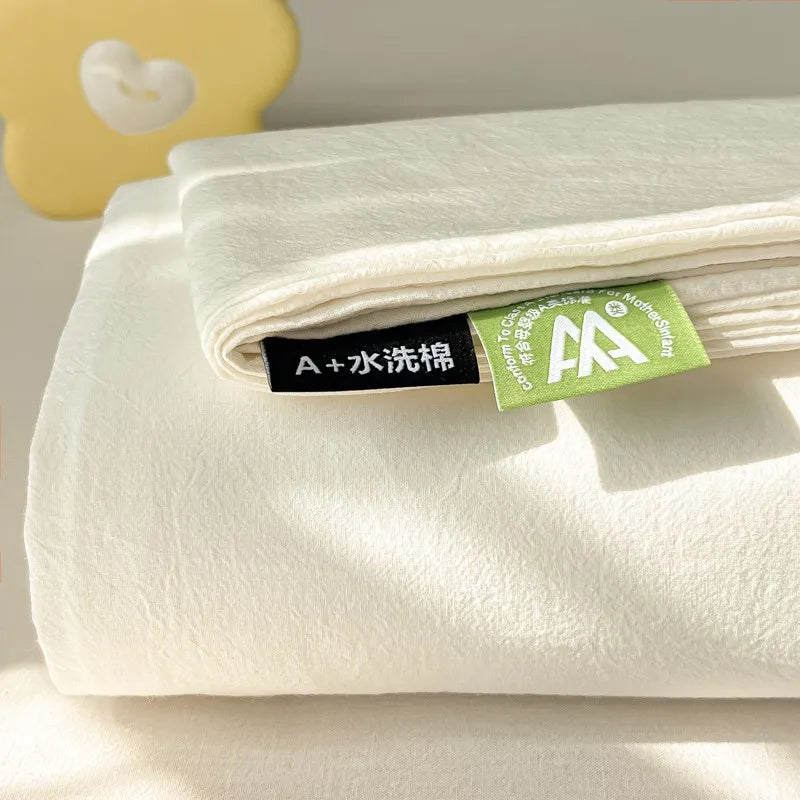 A white organic cotton flat sheet folded with a green laundry tag on a light surface.