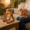 A person is using a wooden rotating yarn storage rack to wind orange yarn, sitting on a sofa.