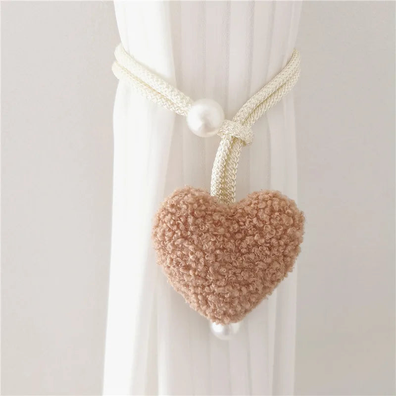 Cream knitted heart tiebacks with pearl accents used to hold white curtains.