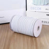 A roll of white adjustable elastic bands for garments resting on a wooden surface next to some books.