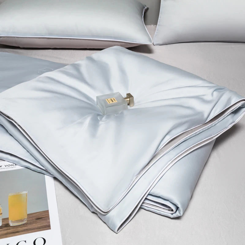 A folded light blue ice silk cooling quilt with a brass zipper visible on the top layer.