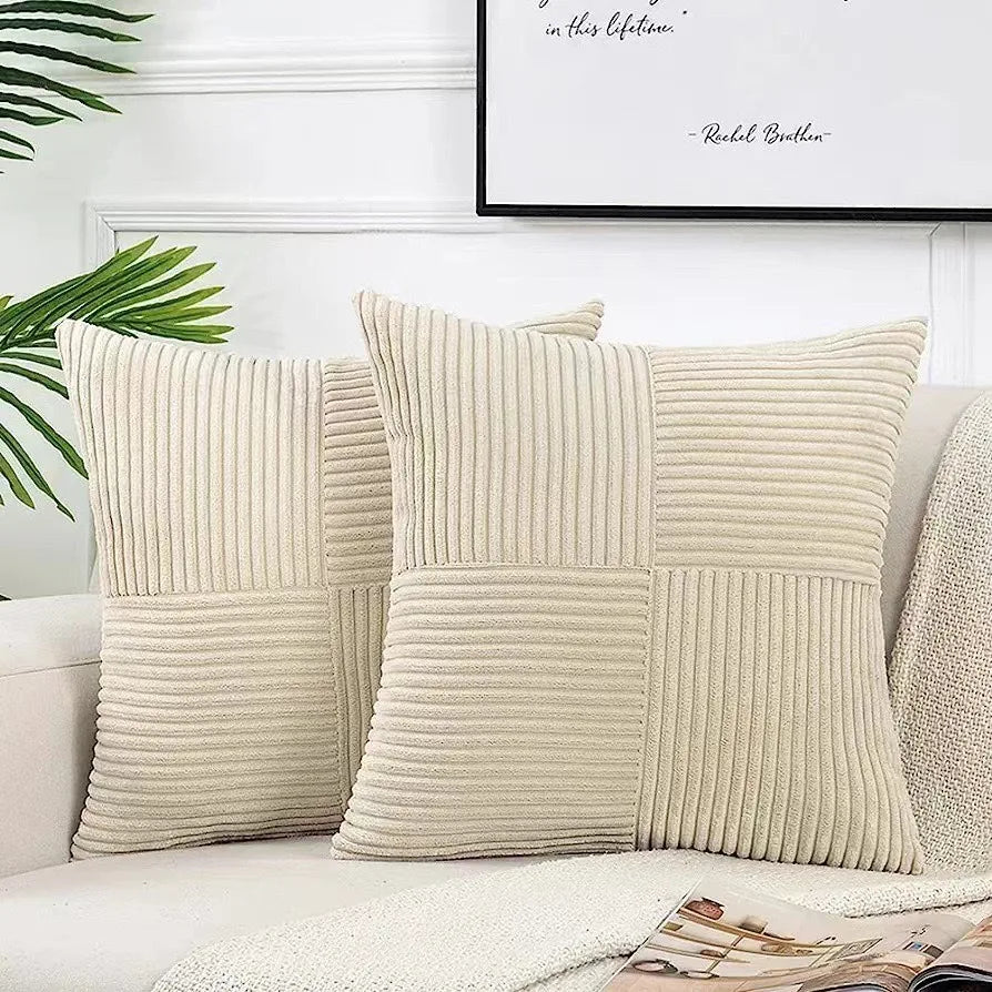 A set of four neutral corduroy throw pillow covers with a vertical ribbed texture and patchwork design on a white sofa.