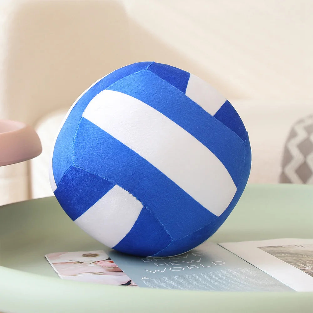 A blue and white striped plush volleyball ball resting on a light green surface.