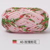 A ball of pink hand-dyed fabric strip yarn featuring a green floral pattern.