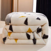 A stack of white fleece blankets with black and yellow floral patterns resting on a light surface.