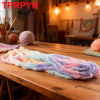 A long piece of multicolored chunky acrylic yarn is displayed on a wooden table.