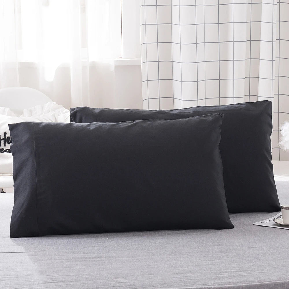 A stack of solid black microfiber pillow covers is displayed on a light gray surface.