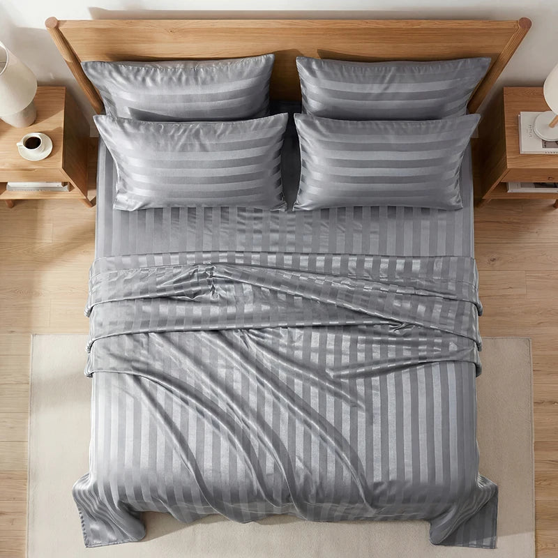 A set of gray striped wrinkle-resistant satin bedding with matching pillows on a wooden bed frame.