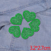 Five green glitter heart star patches sewn onto a denim fabric