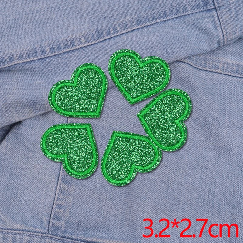 Five green glitter heart star patches sewn onto a denim fabric