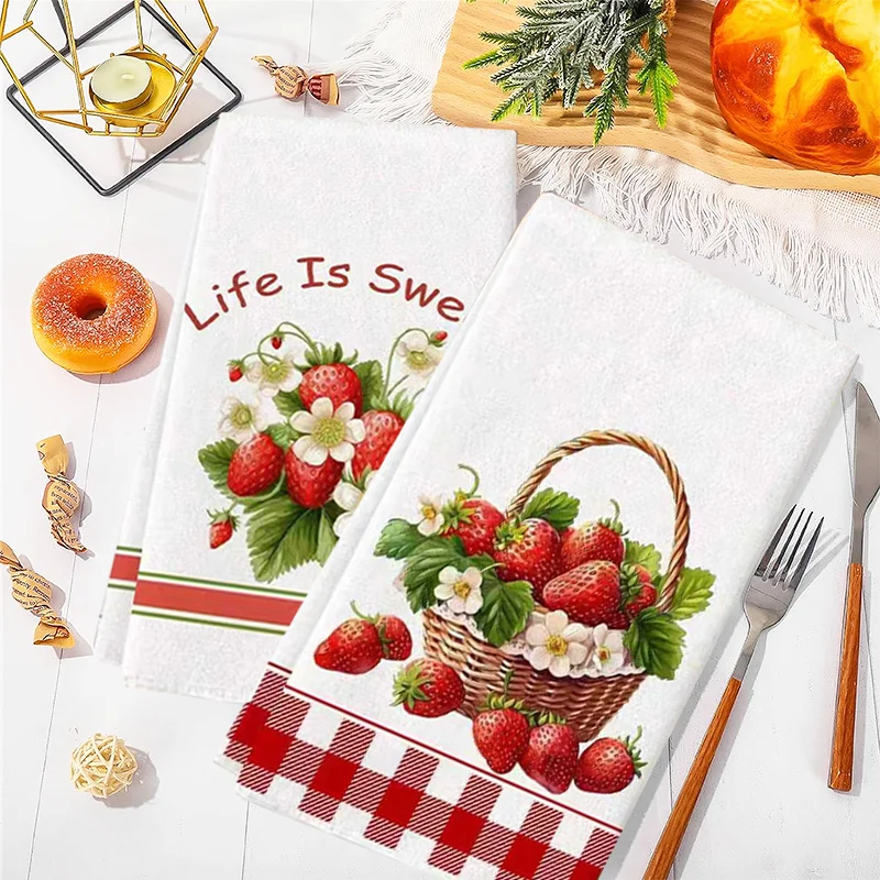 A set of two white kitchen towels featuring a strawberry design on one and a red checkered pattern on the other.