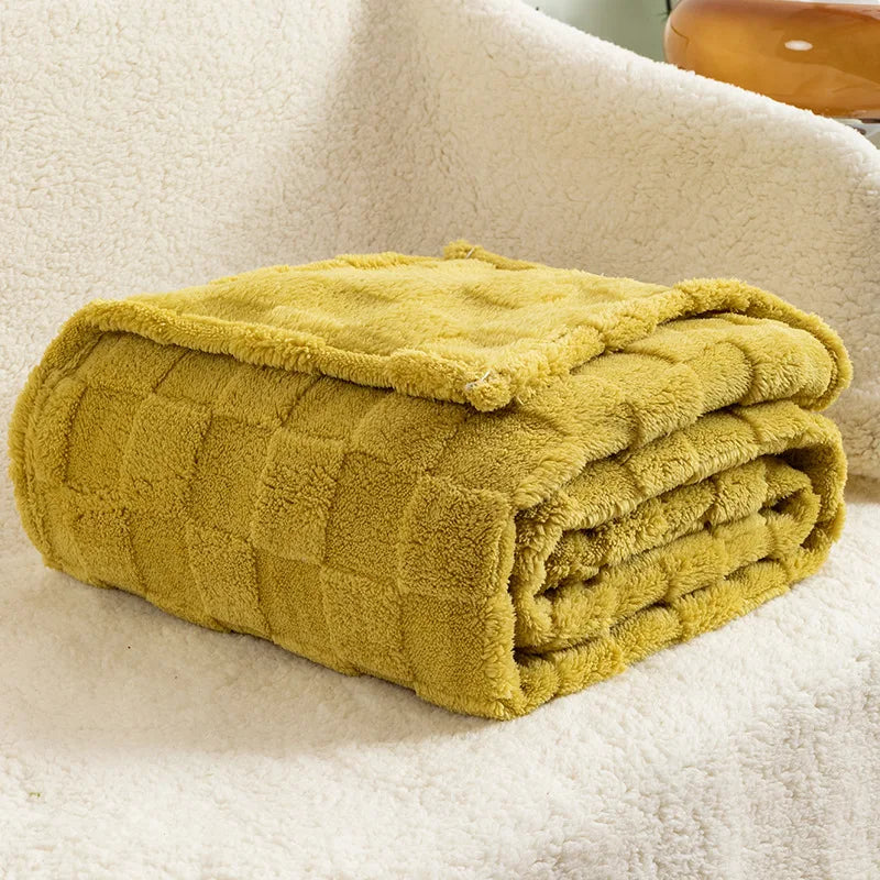 A thick, mustard yellow checkered fleece throw blanket folded neatly on a white textured surface.
