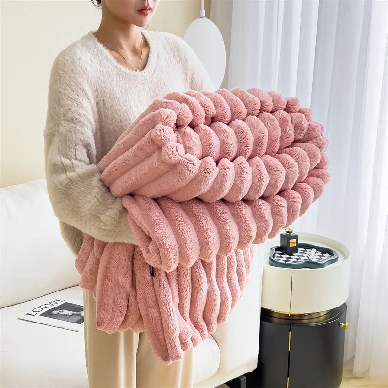 A person is holding a large, fluffy pink plush blanket with textured ridges in a bright indoor setting.